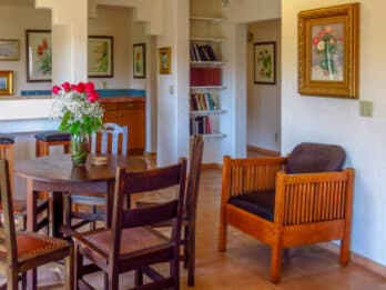 A cozy dining area featuring a round table, wooden chairs, and floral decorations.