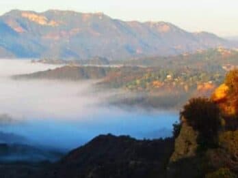 A foggy valley with mountains in the background at sunrise.