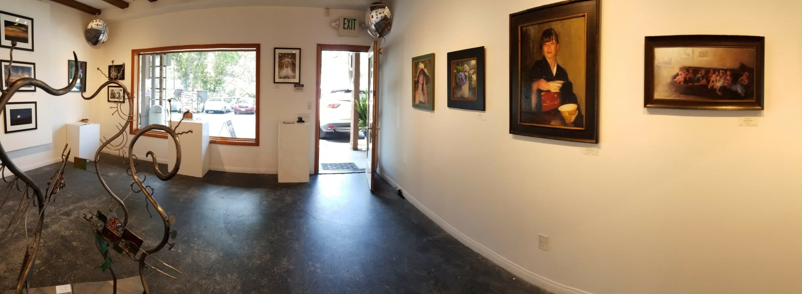 A panoramic view of an art gallery featuring various paintings and a sculpture.