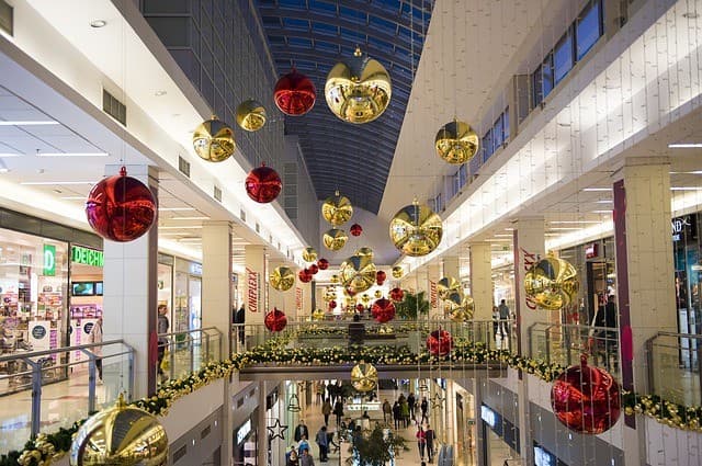 A bustling shopping mall decorated with large red and gold ornaments hanging from the ceiling.