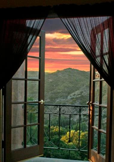 Open double doors reveal a sunset view over rolling hills.