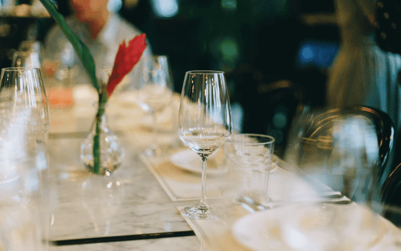 A beautifully set dining table with elegant glassware and a decorative flower centerpiece.