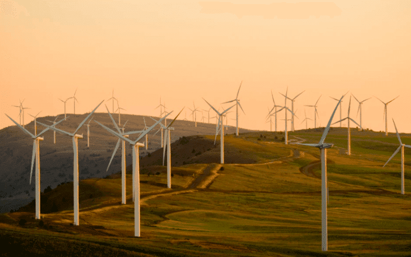 A landscape featuring multiple wind turbines against a sunset backdrop. A landscape featuring multiple wind turbines against a sunset backdrop.