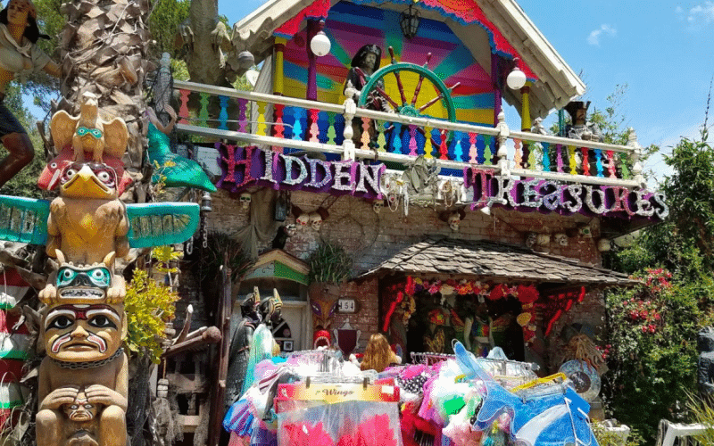 A vibrant storefront with the sign "Hidden Treasures" surrounded by colorful decorations and sculptures. A vibrant storefront with the sign "Hidden Treasures" surrounded by colorful decorations and sculptures.