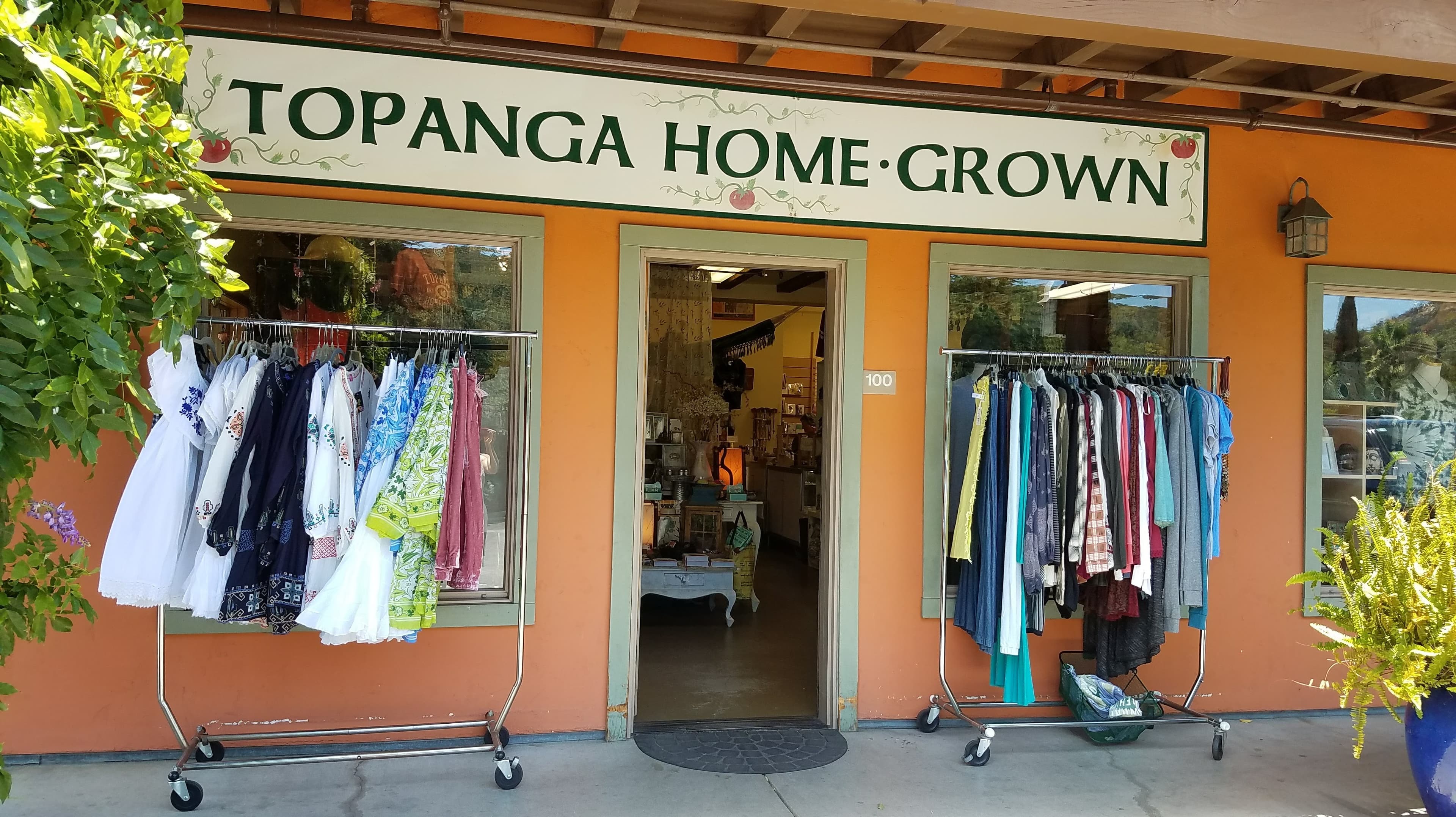 Exterior of "Topanga Home Grown" store with clothes racks displaying various garments.